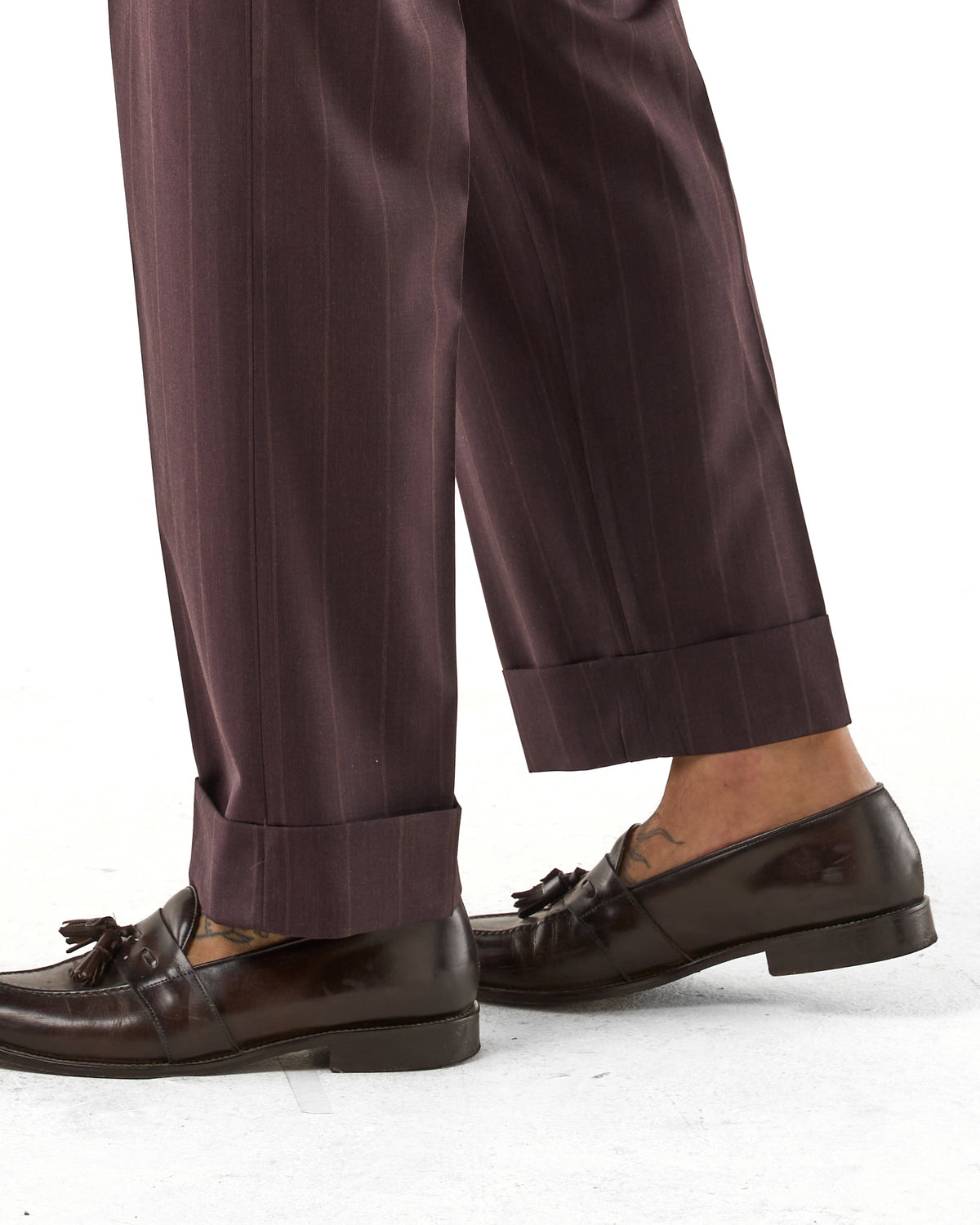 Pantalones de pernera ancha color ciruela con rayas beige y hebillas laterales.